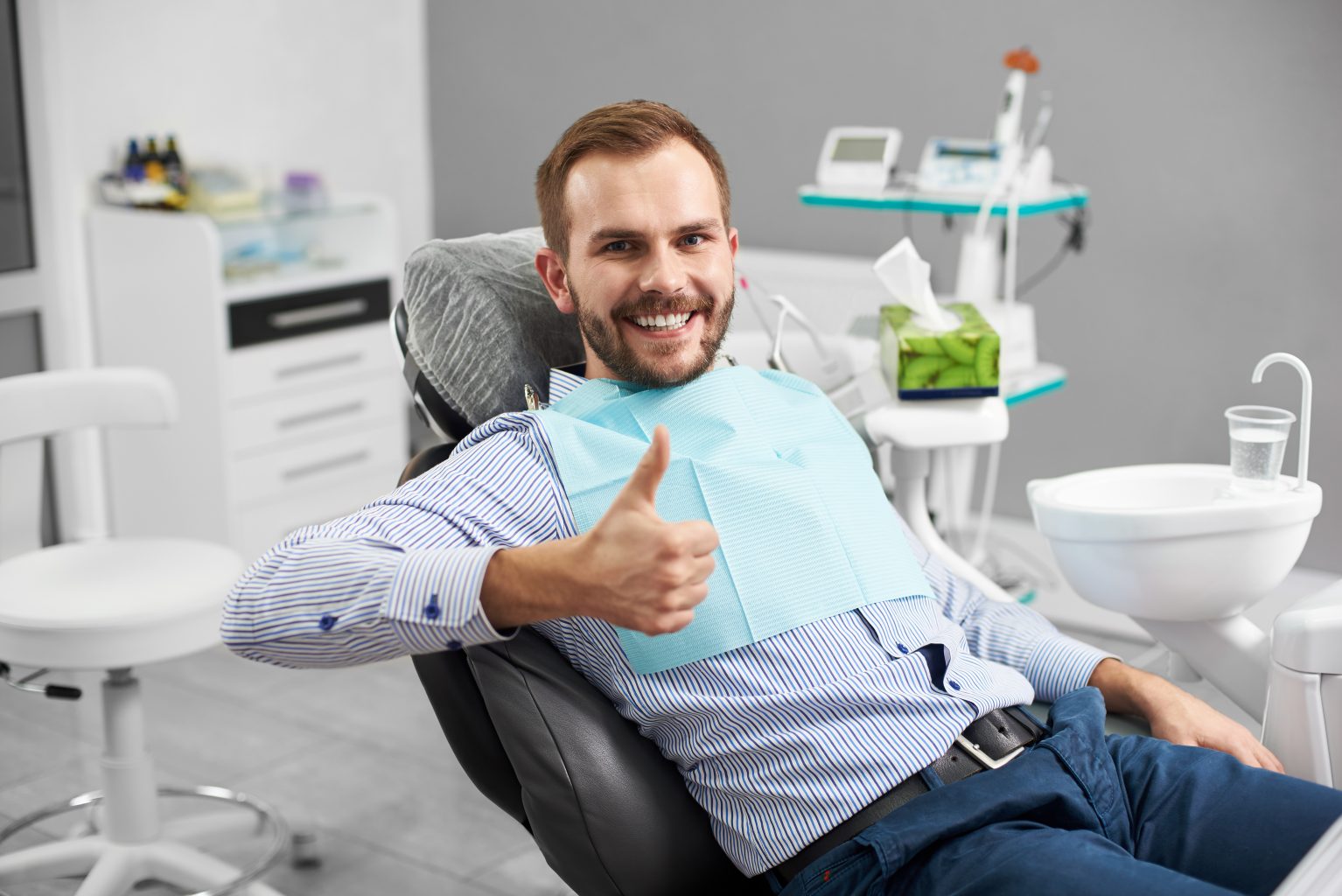 Portrait Of Happy Patient In Dental Chair And Shows A Gesture With A Thumb Up Class, Good. Modern Dentistry With The Use Of New Technologies